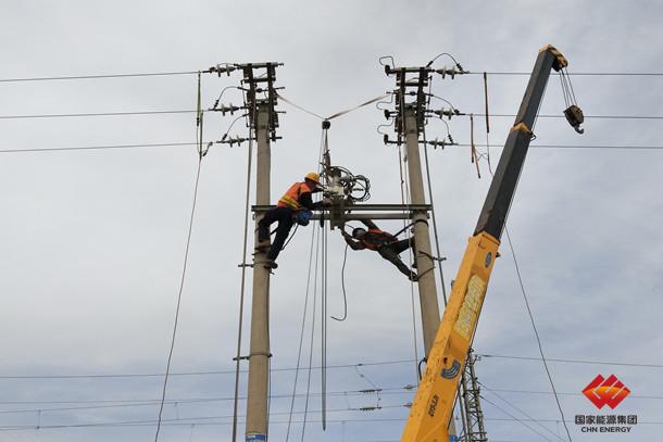 图为施工作业人员正在吊装新型断路器